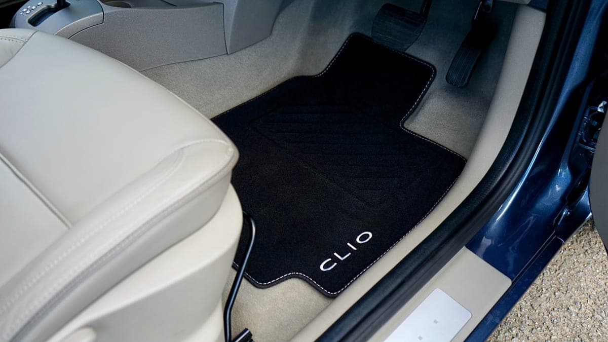 The carpeted floor of a car footwell in daylight