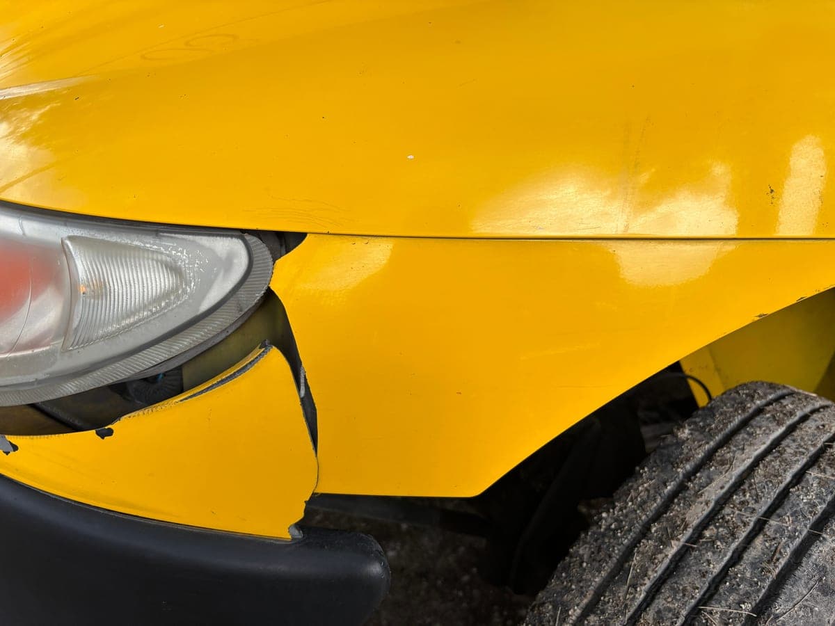 A dented rear bumper and scraped paintwork on a parked car