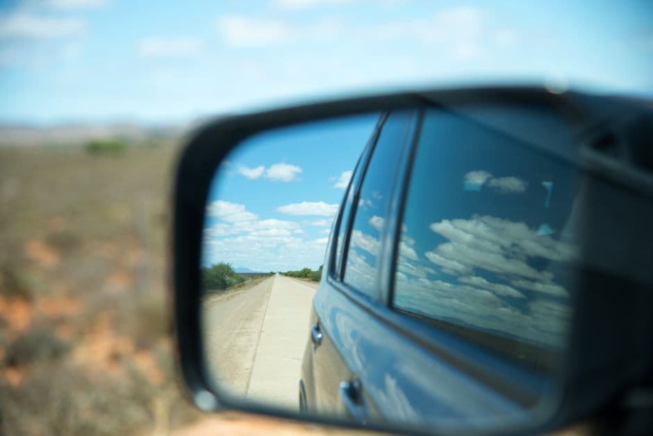A car side mirror showing the lane alongside