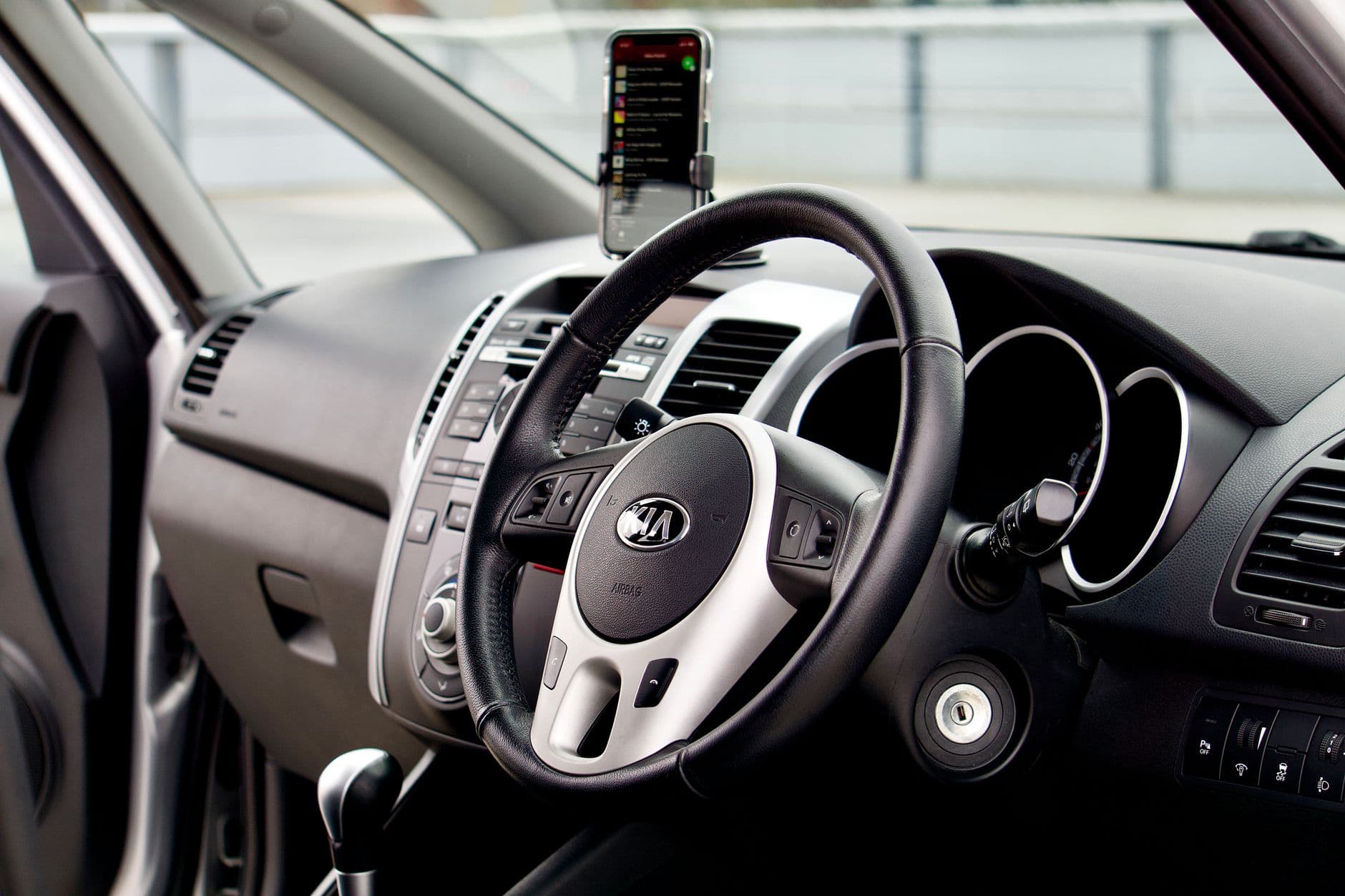 A phone mounted on an air vent in an unfamiliar car with luggage on the back seat