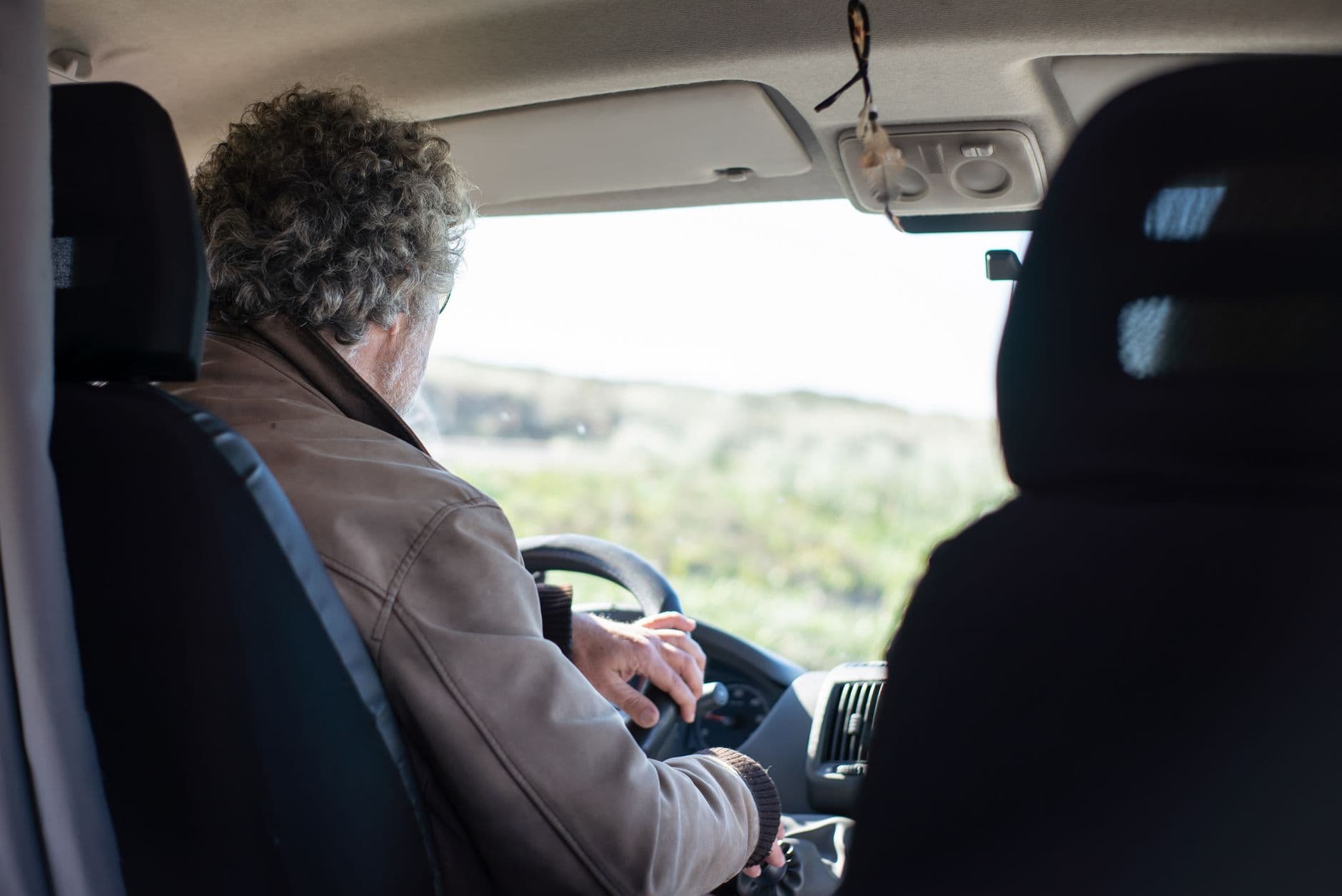 An older driver adjusting the rear view mirror before setting off