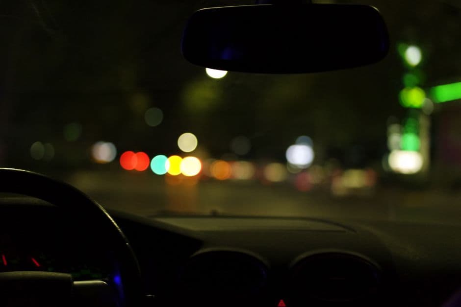 A car interior seen from the driver's seat at night in a city