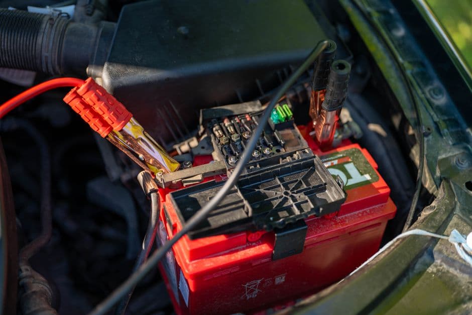 A car battery under an open hood with terminals visible