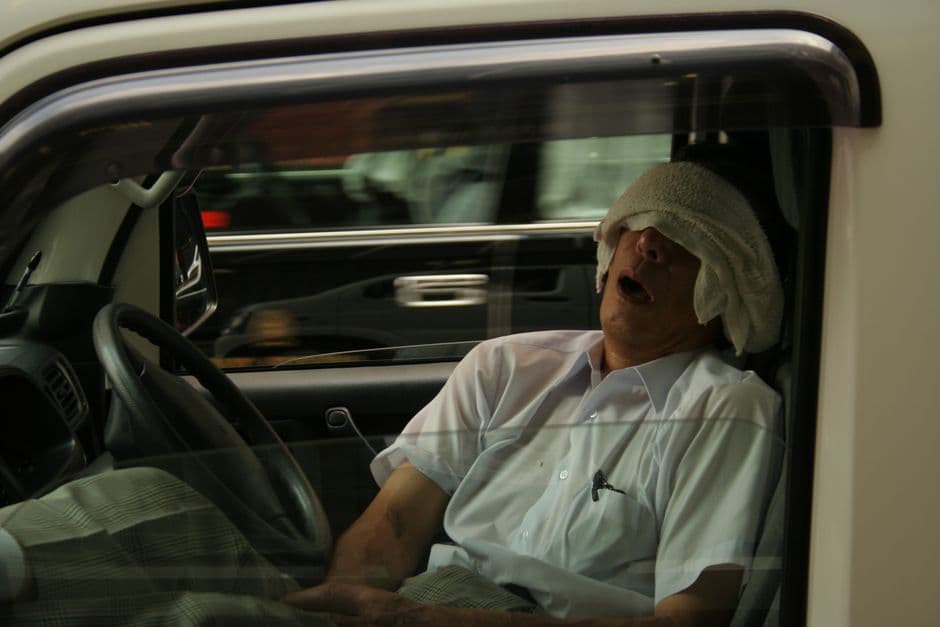 A passenger resting against a car seat headrest