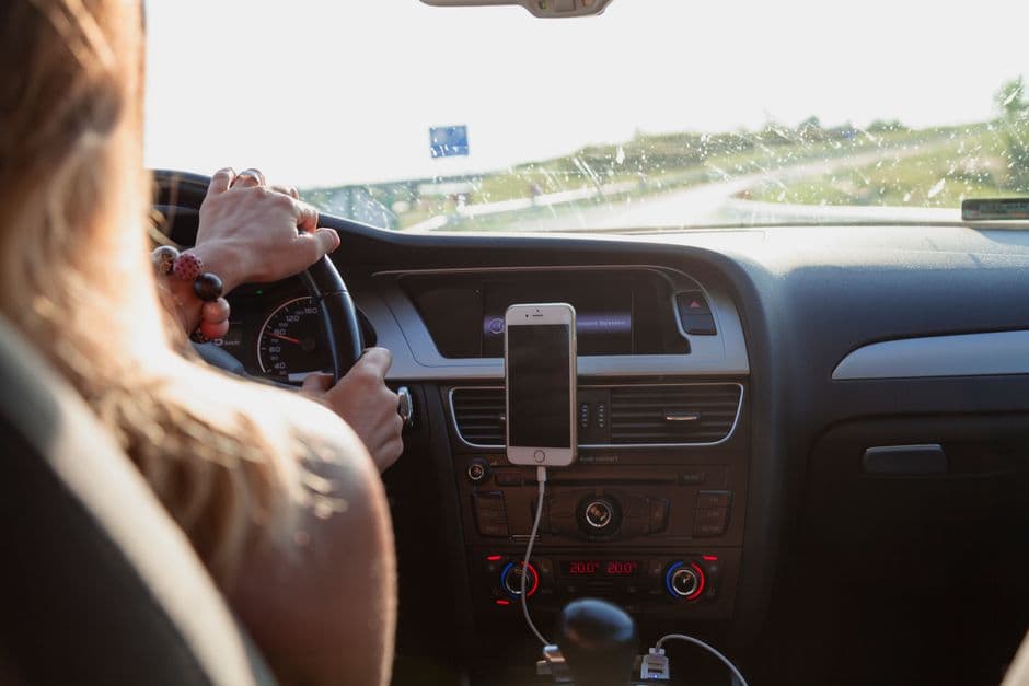 A smartphone mounted in a car with the road visible ahead