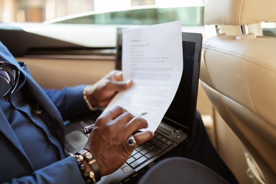 A laptop and documents on a car's passenger seat