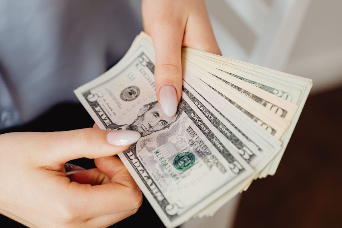A pair of hands holding folded banknotes