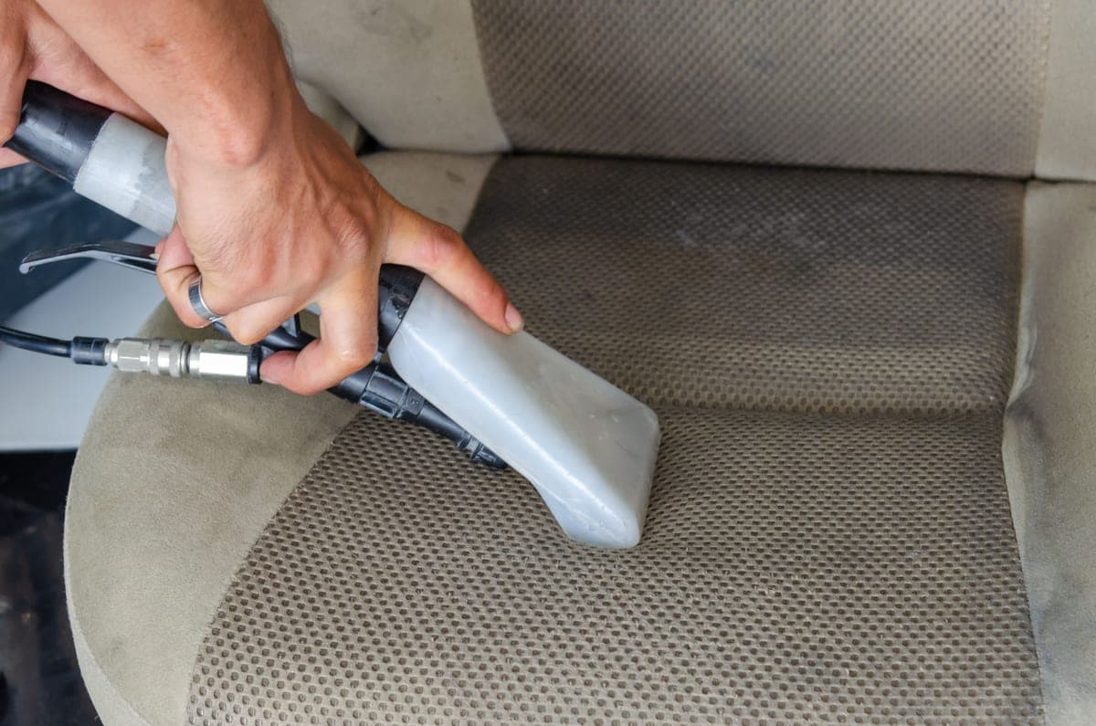 A vacuum nozzle cleaning the seat of a car interior
