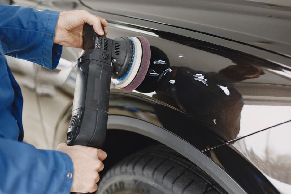 A hand polishing the painted panel of a car