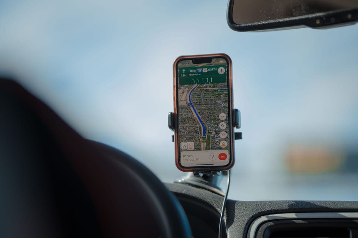 A phone in a holder mounted on a car dashboard showing a navigation map