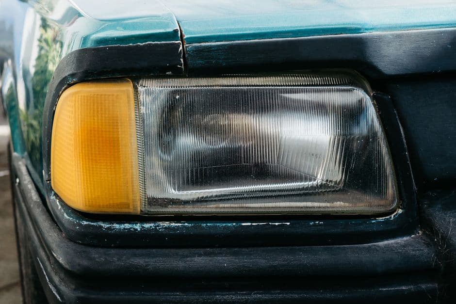 A cloudy yellowed car headlight lens in close detail