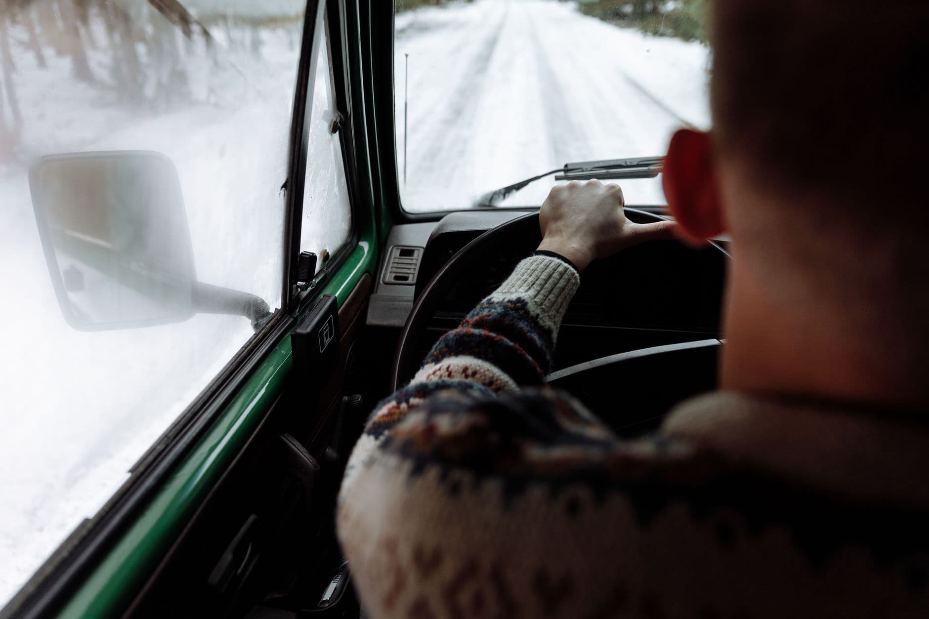 Gloved hands resting on a padded steering wheel cover on a frosted winter morning