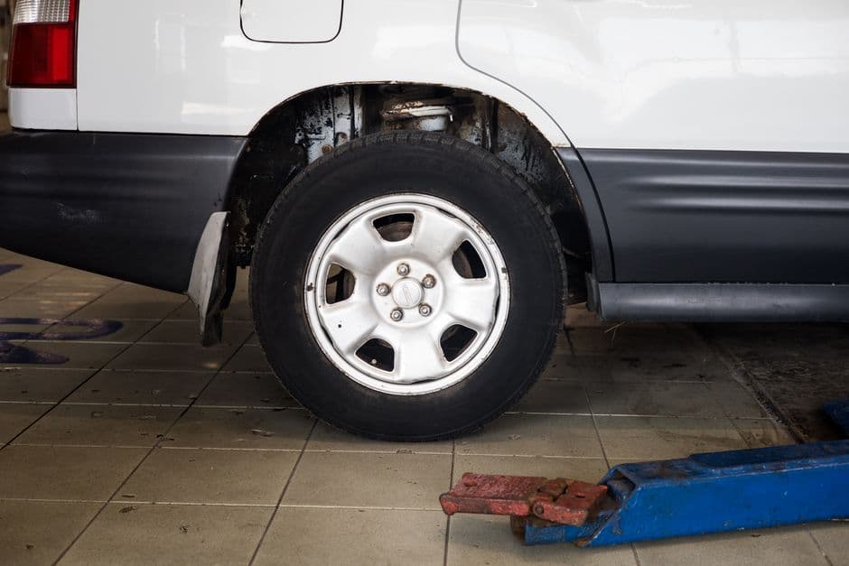 A car raised on a jack with a stand positioned beneath it