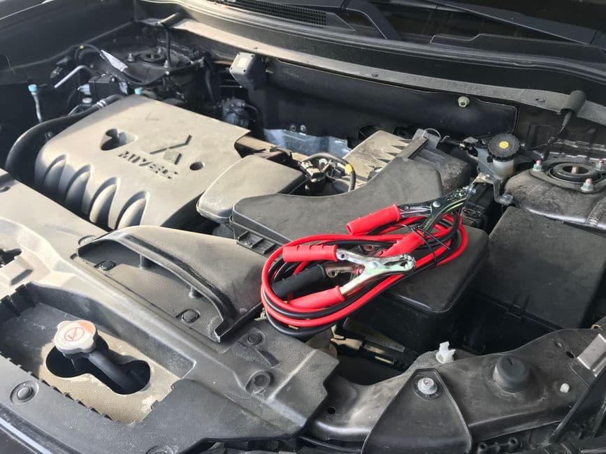 A portable jump starter connected to a car battery at the roadside
