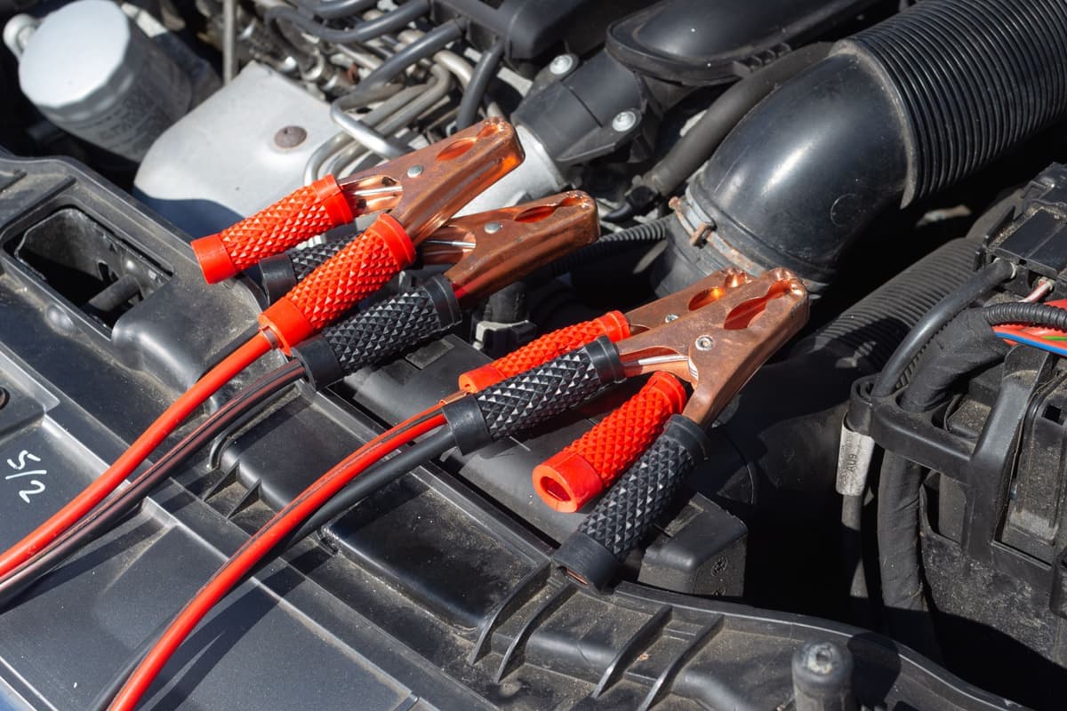 Jump leads clamped to a car battery in an engine bay