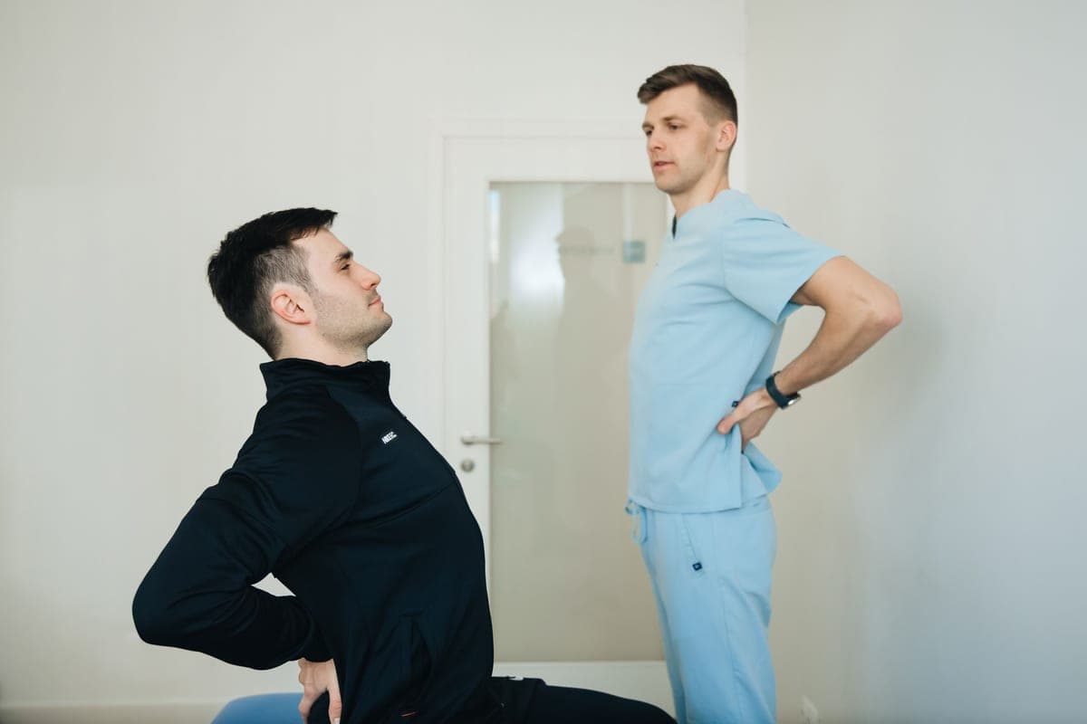 A person seated upright with a hand resting against their lower back