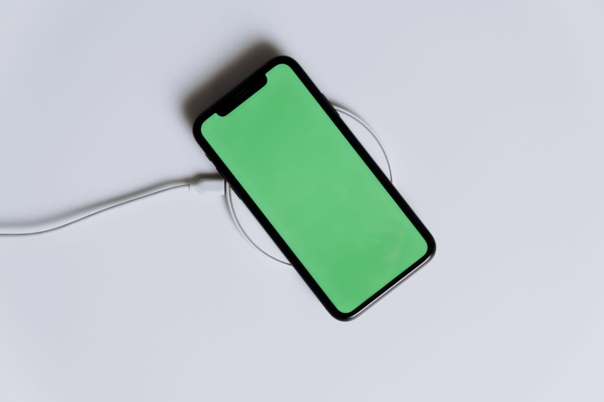 A smartphone resting on a round magnetic wireless charging pad