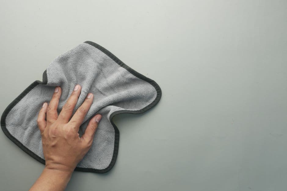 Folded microfiber cloths stacked beside a car panel