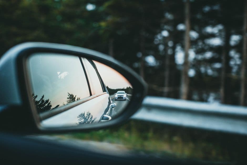 A car rear view mirror reflecting the road behind