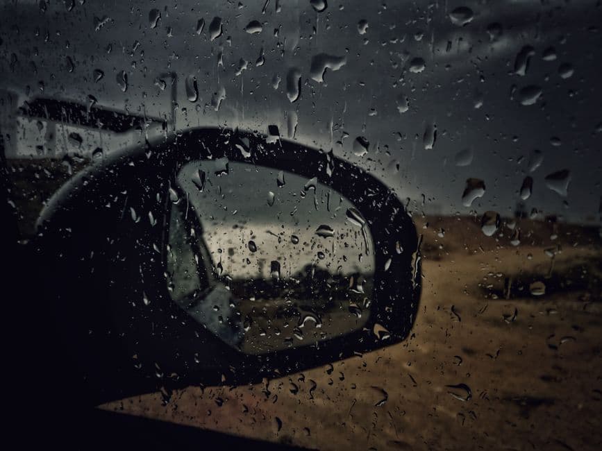 Rain running down the side window of a parked car