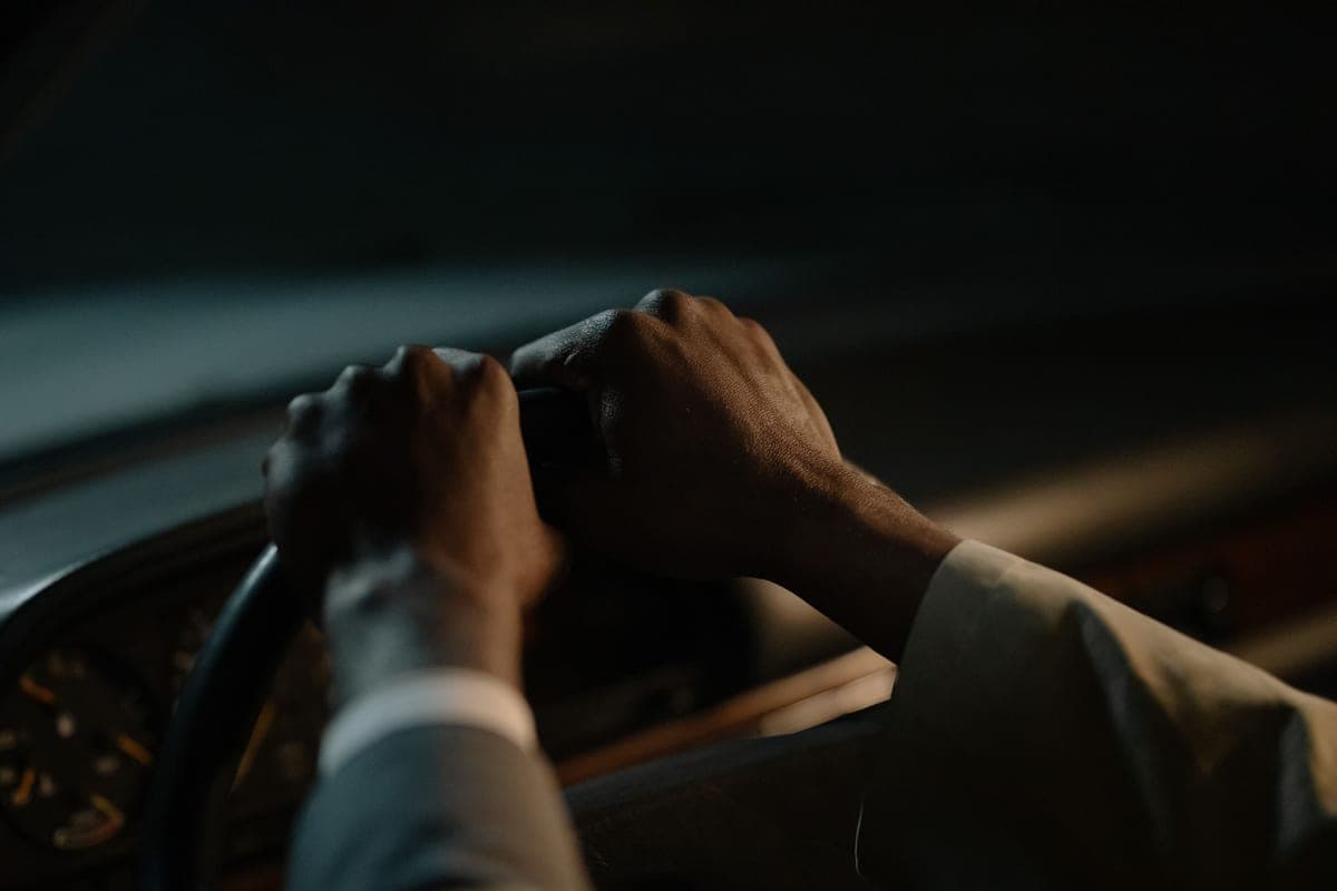 A pair of hands gripping a car steering wheel