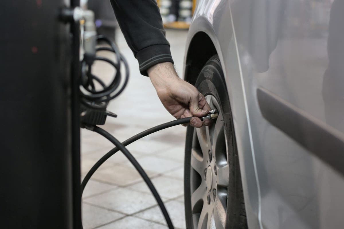 A person checking the air pressure of a car tire with a gauge