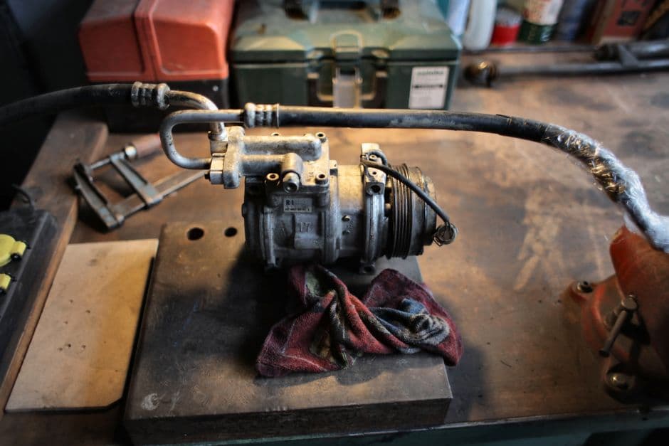 A clean pleated air filter beside a dirty one on a workbench