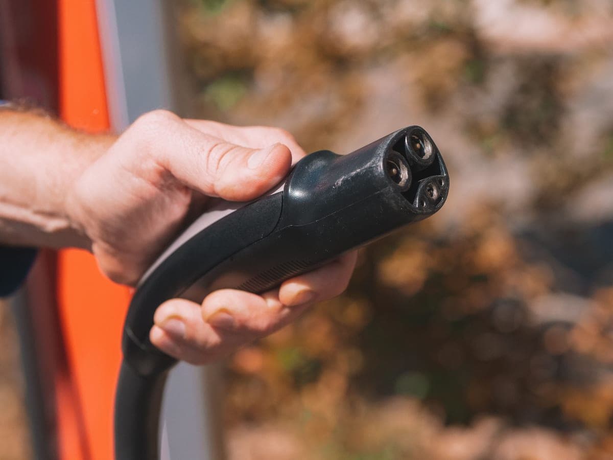 An electric vehicle charging connector plugged into a car's charge port