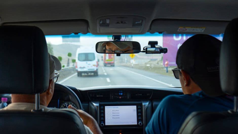 A small camera mounted behind a car's rear view mirror