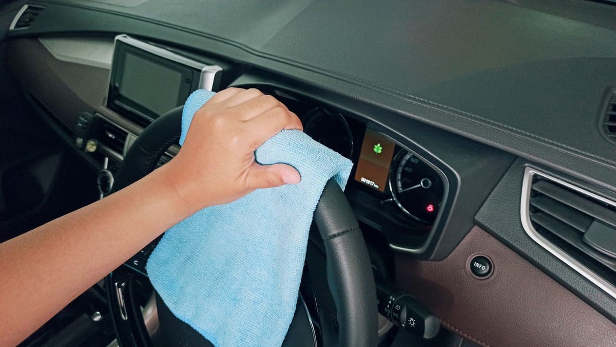 A person wiping a car dashboard with a cloth