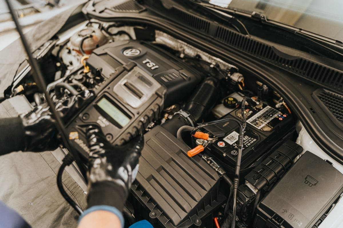 A car battery and terminal clamps visible in an open engine bay