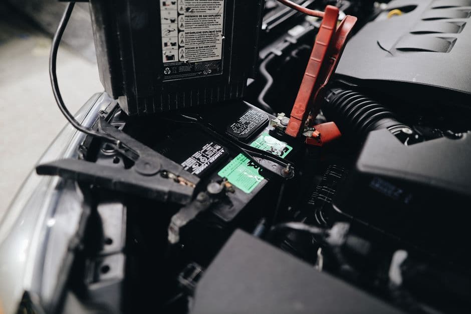 A compact lithium jump starter with clamps beside a USB power bank