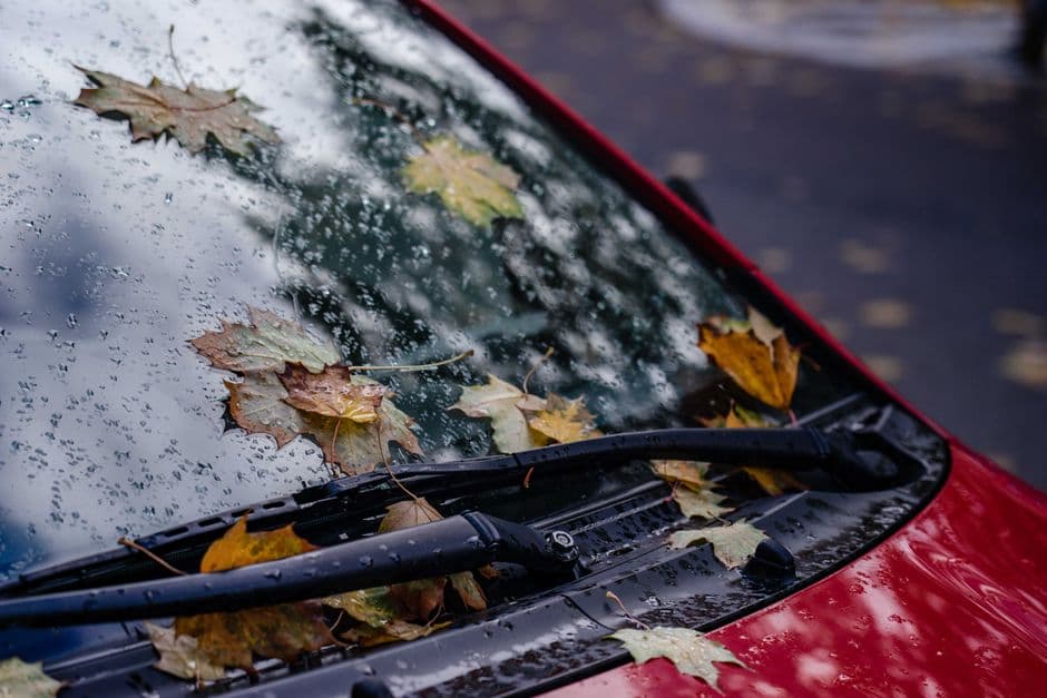 Rain beading on a car windshield with a wiper blade mid-sweep