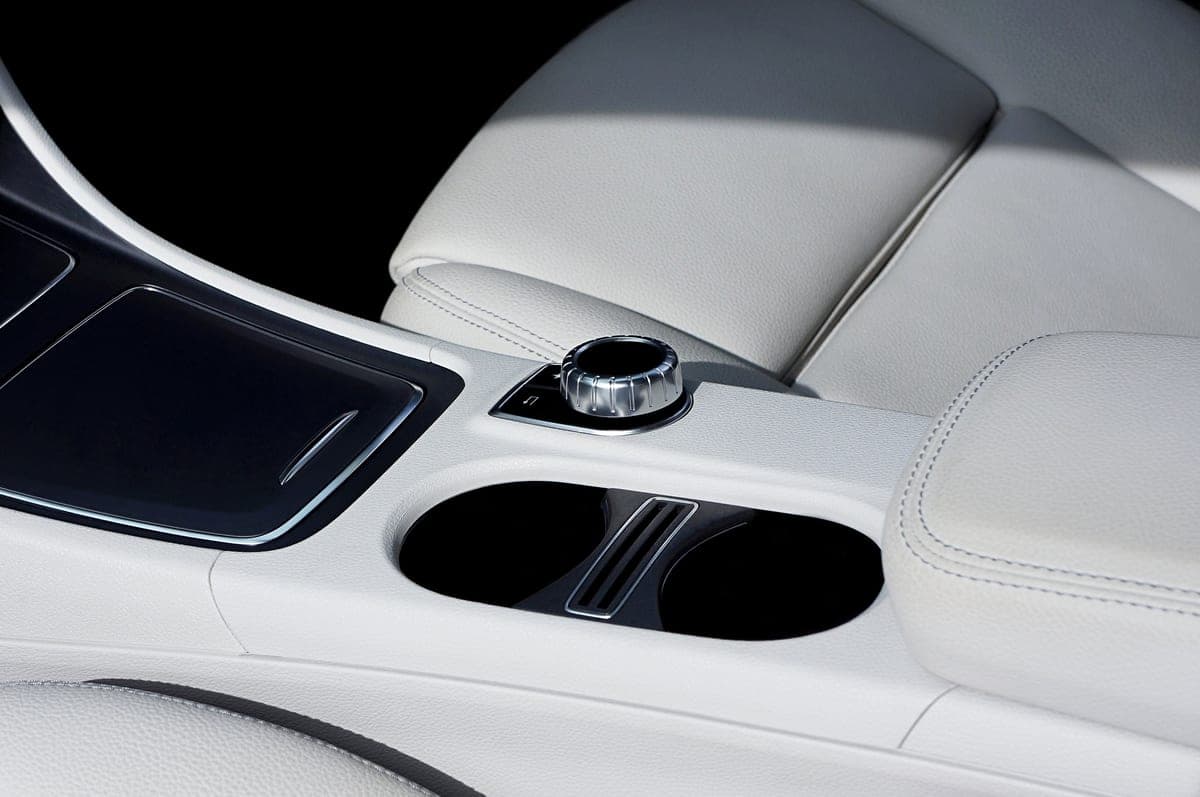 A car's center console with cup holders and a gear selector