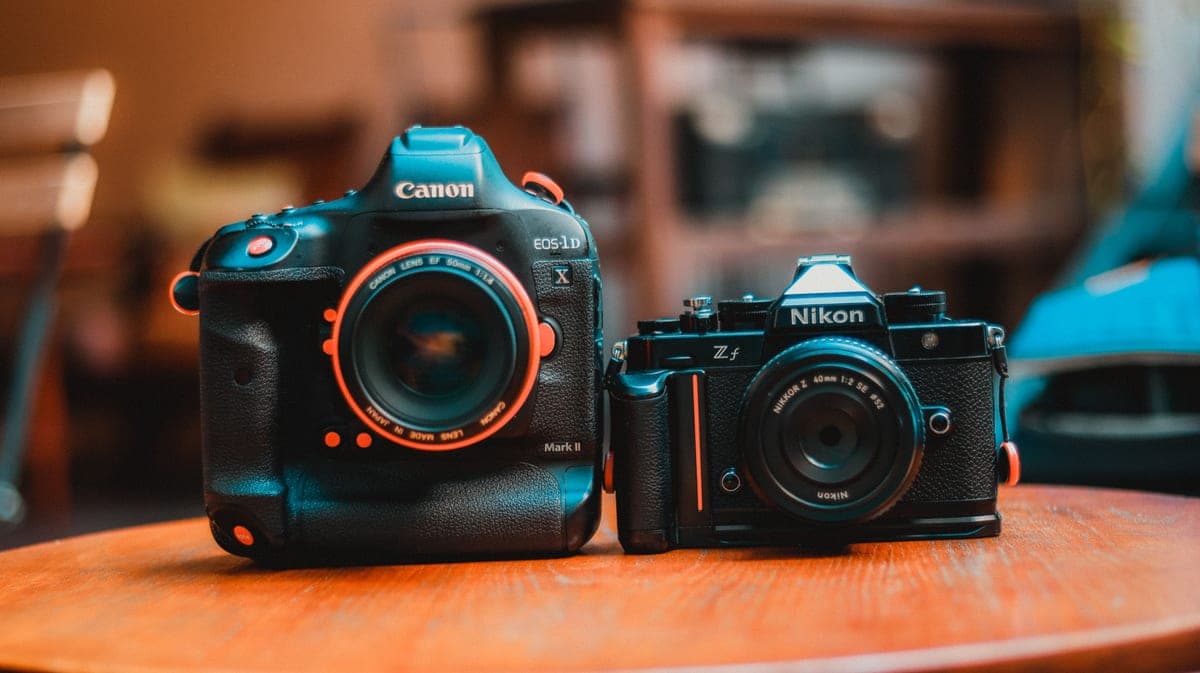 Two small camera devices photographed side by side on a plain surface
