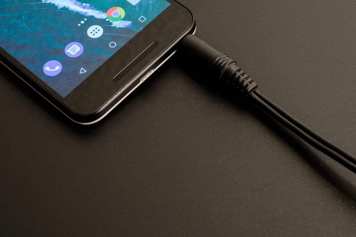 A USB cable plugged into a phone resting in a car's center console