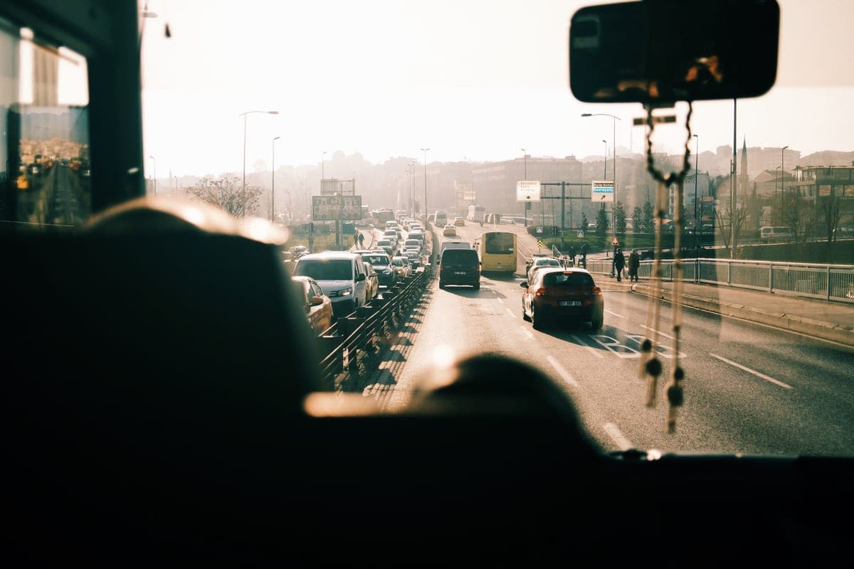 A view through a car windshield of a multi-lane highway at sunrise