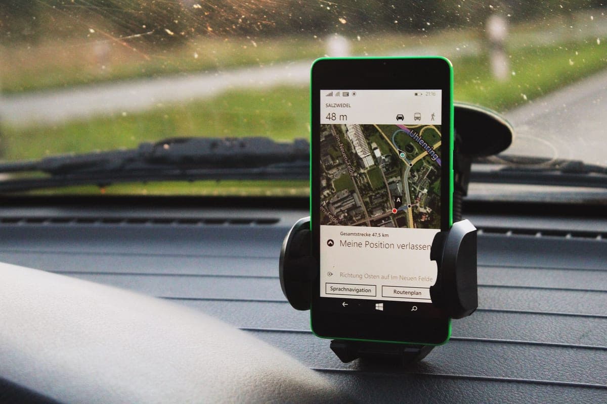 A smartphone held in a black mount clipped to a car's dashboard air vent