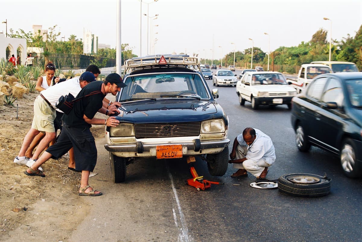 A car tire and wheel photographed at the roadside next to a highway shoulder